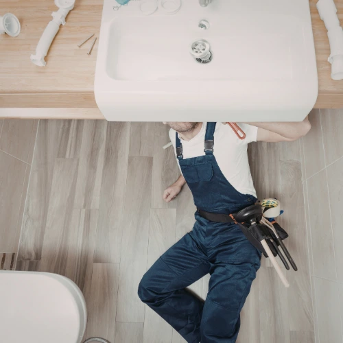 Handyman fixing leaking faucet in home bathroom